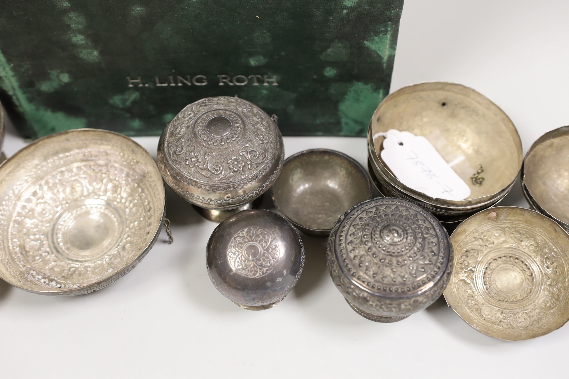 A collection of Malay Straits white metal circular betel nut boxes ('Chimbul'), comprising seven boxes and covers of various sizes (some damaged or missing chain fastenings) and two boxes lacking covers, gross weight 881